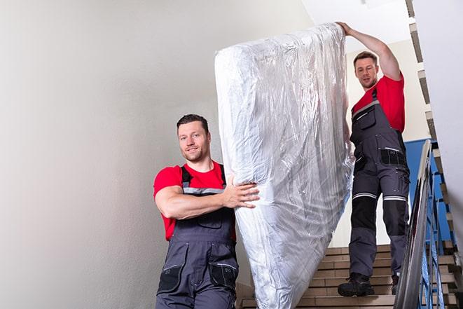 two workers carrying a heavy box spring out of a bedroom in Big River, CA